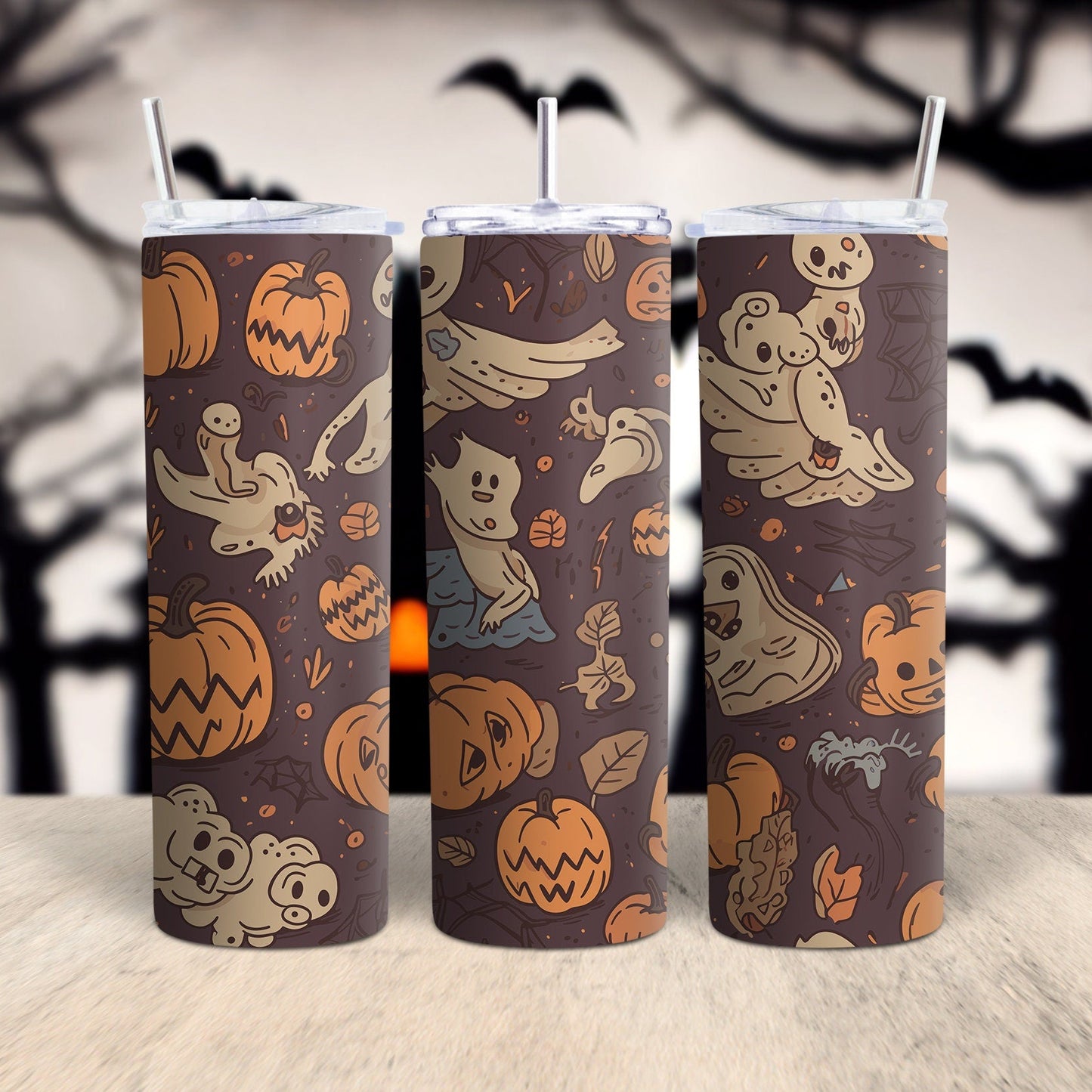 Three Halloween-themed tumblers with pumpkins, ghosts, and bats on a wooden surface with a spooky tree background.
